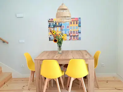 a dining room table with yellow chairs and a vase of flowers at Boavista Luxury Villas in Porto