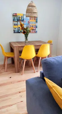 a dining room with a wooden table and yellow chairs at Boavista Luxury Villas in Porto