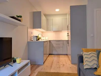 a kitchen with white cabinets and a couch in a living room at Boavista Luxury Villas in Porto