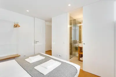 a white room with a bed and a mirror at Miragaia Apartments by DA'HOME in Porto