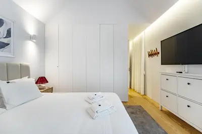 a white bedroom with a large bed and a flat screen tv at Nomad's Lux - Almada Apartments Porto in Porto