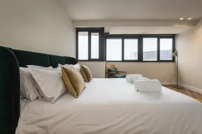a large white bed in a room with windows at Aspasios Bonjardim Apartments in Porto