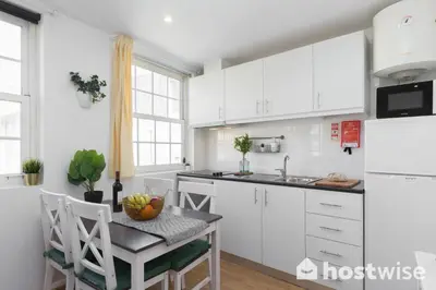 a kitchen with white cabinets and a table at Host Wise - Colorful Fresh Flats - Batalha in Porto