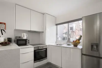 a kitchen with white cabinets and a stainless steel refrigerator at Host Wise - Spacious Noble Apartaments Ace Location in Porto