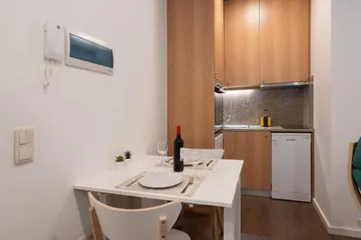 a small kitchen with a white table with a bottle of wine at Host Wise - Modern Studios with Terrace - Walk Everywhere in Porto