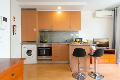 a kitchen with wooden cabinets and black bar stools at Host Wise - Bright Quiet Flats - Prime Location in Porto