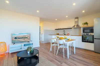 a kitchen with white cabinets and a table and chairs at Host Wise - Fantastic Contemporary Flat w Balcony in Porto
