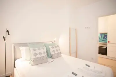 a white bedroom with a white bed with pillows at Liiiving in Porto - Urban Art Apartment in Porto