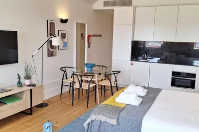 a room with a bed and a table and a kitchen at Fontainhas Hidden Gem in Porto