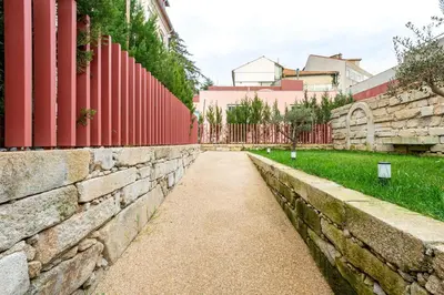 a stone wall and a sidewalk next to a fence at Fontainhas Hidden Gem in Porto