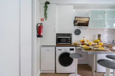 a kitchen with a washing machine and a table with fruit at Host Wise - Modern Flats with Stunning Terrace or Balcony - Central Location in Porto