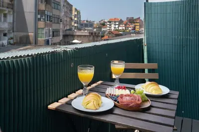a wooden table with two glasses of orange juice and food at Host Wise - Modern Flats with Stunning Terrace or Balcony - Central Location in Porto