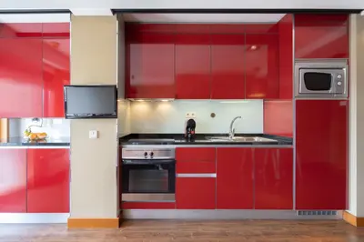 a red kitchen with a sink and a microwave at Host Wise - Bright Fresh Flat with Garage - Marquês in Porto