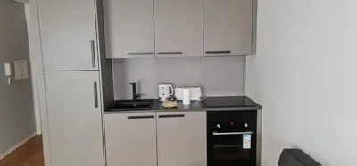a kitchen with white cabinets and a black appliance at Campanhã Studio in Porto
