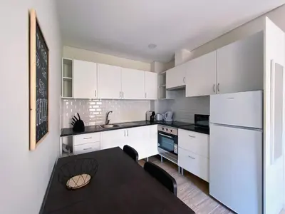 a kitchen with a black table and white cabinets at Casas S. Dinis in Porto