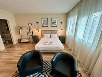 a bedroom with two chairs and a bed with white sheets at Lemago Porto Apartments - Bonjardim in Porto
