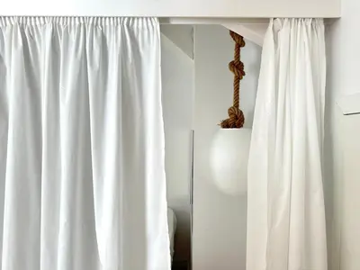 a white curtain in a white room with a table at Art Cottage with oPorto View! in Vila Nova de Gaia