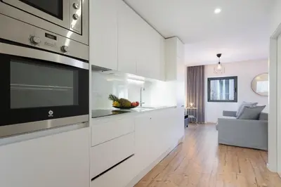 a kitchen with white cabinets and a living room at Host Wise - Charming Welcoming Flat - Centrally Located in Porto
