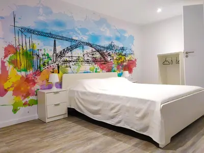 a bedroom with a bed and a painting of a bridge at OLOPO Hostel in Porto