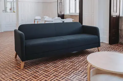a black couch in a room with tables and chairs at OLOPO Hostel in Porto