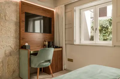 a bedroom with a desk with a television and a chair at Ribeira Douro Hotel in Porto