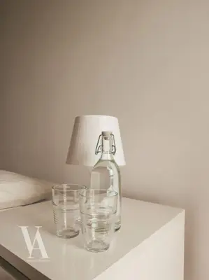 a bottle and two glasses on a table with a lamp at Voga Apartments Marquês in Porto
