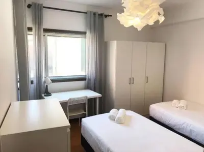 a room with two beds and a desk and a window at Covelo 90 in Porto