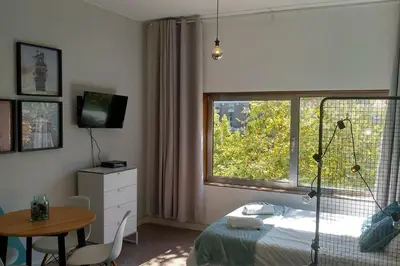 a bedroom with a bed and a table and a window at Trindade City Studio 77 in Porto