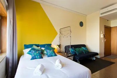 a bedroom with a white bed with blue pillows and a chair at Trindade City Studio 77 in Porto