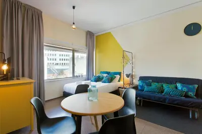 a hotel room with a bed and a table and a couch at Trindade City Studio 77 in Porto