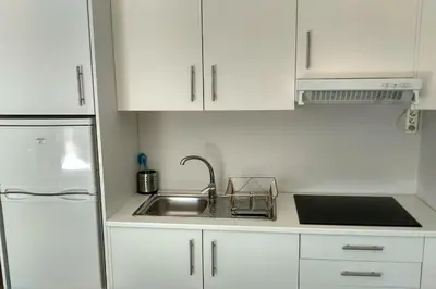 a white kitchen with a sink and a refrigerator at Trindade City Studio 77 in Porto