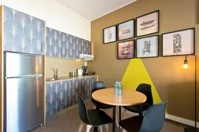 a dining room with a table and chairs and a refrigerator at Trindade City Studio 77 in Porto