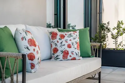 a white couch with red and green pillows on a balcony at BONFIM LIVING - Great location, al fresco dining and free private parking in Porto
