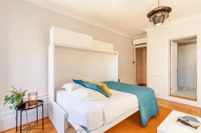 a white bedroom with a bed with blue and white pillows at D&S - Palácio dos Príncipes in Porto