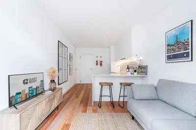 a white living room with a couch and a kitchen at GuestReady - Tranquility in downtown in Porto