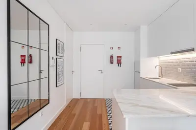 a white kitchen with a counter and a glass wall at GuestReady - Tranquility in downtown in Porto