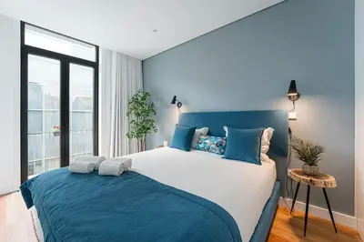 a bedroom with a blue and white bed with a window at GuestReady - Tranquility in downtown in Porto