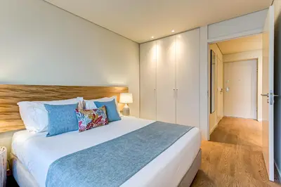 a bedroom with a large white bed with blue pillows at Blissful Suites Porto by gaiarooms in Porto