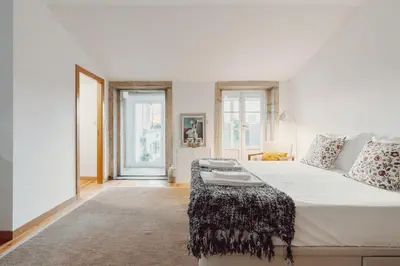 a bedroom with a large white bed with a table at Papa Apartment with Terrace in Porto
