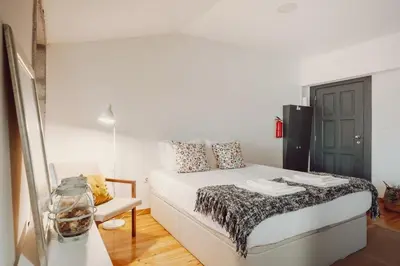 a white bedroom with a bed and a chair at Papa Apartment with Terrace in Porto