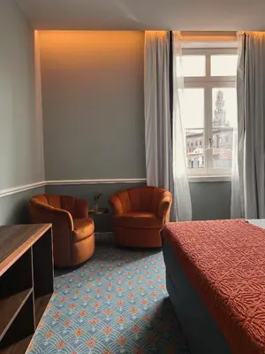 a hotel room with a bed and chairs and a window at GRANDE HOTEL PARIS by STAY HOTELS in Porto