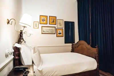 a bedroom with a bed with a lamp and pictures on the wall at GRANDE HOTEL PARIS by STAY HOTELS in Porto