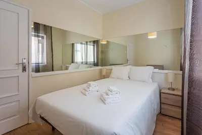 a bedroom with a white bed with a large mirror at GuestReady - October Tide in Porto