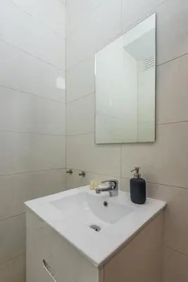 a white bathroom with a sink and a mirror at GuestReady - October Tide in Porto