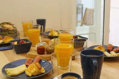 a table with plates of food and glasses of orange juice at Nº 91 - Almirante Guest House in Porto