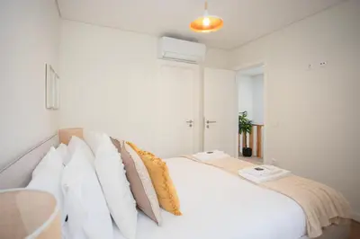 a white bedroom with a large white bed with pillows at Liiiving in Porto - Downtown Quiet House in Porto
