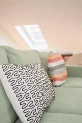 a pillow sitting on a green couch with a window at Liiiving in Porto - Cedofeita Green Terrace in Porto