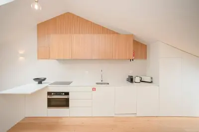 a kitchen with white counters and wooden cabinets at Liiiving in Porto - Cedofeita Green Terrace in Porto