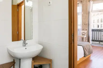 a bathroom with a sink and a mirror and a bed at Stay in Apartments - S. Bento in Porto