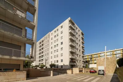 a tall white building with cars parked in a parking lot at Modern Cedofeita by Hosty in Porto